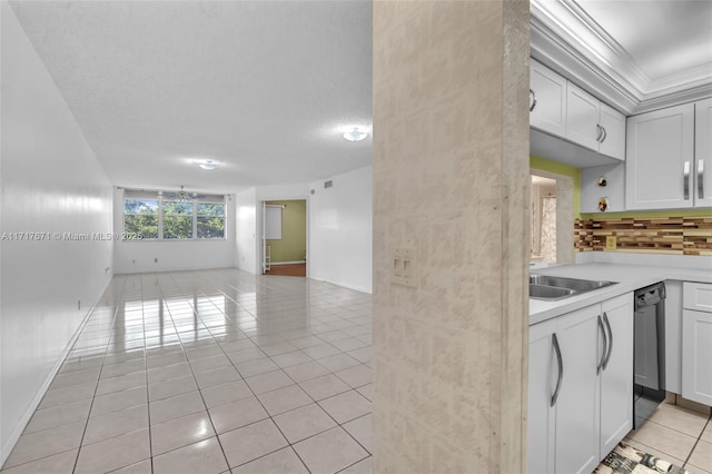 kitchen with tasteful backsplash, sink, light tile patterned floors, and white cabinets