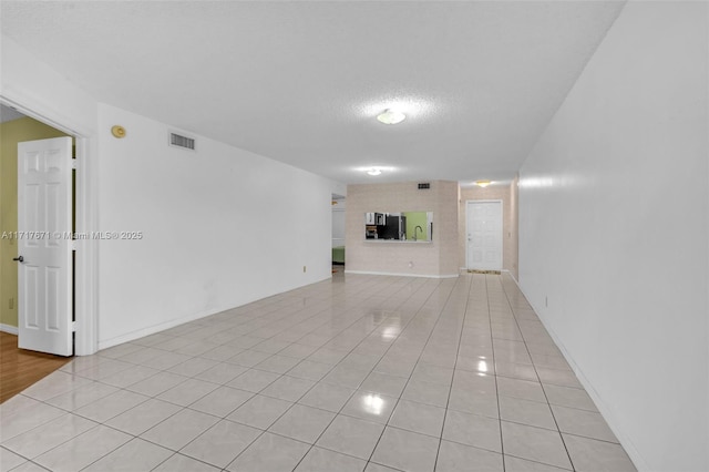 tiled empty room featuring a textured ceiling