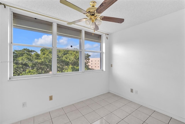 tiled empty room with ceiling fan and a textured ceiling