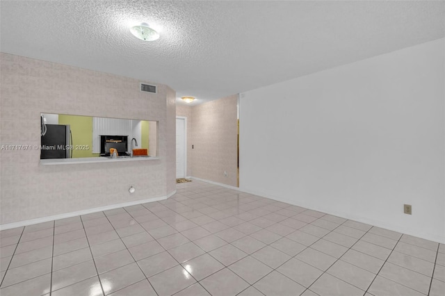 tiled empty room with sink and a textured ceiling