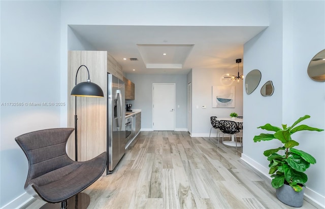 hall with a tray ceiling and light wood-type flooring