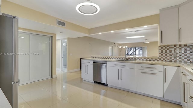 kitchen with appliances with stainless steel finishes, pendant lighting, white cabinetry, sink, and backsplash