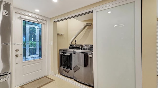 clothes washing area featuring washer and clothes dryer and light tile patterned floors