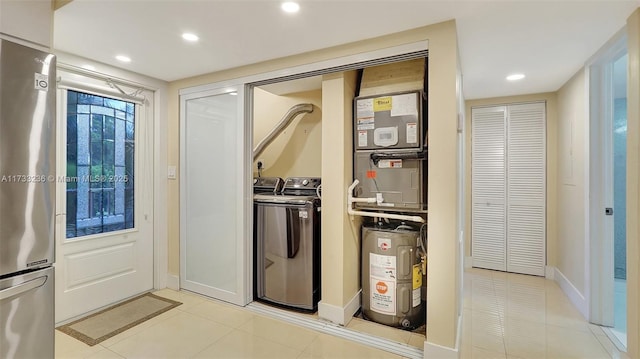 interior space featuring heating unit, light tile patterned floors, stainless steel fridge, independent washer and dryer, and water heater