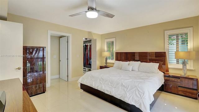 bedroom featuring light tile patterned floors, a walk in closet, a closet, and ceiling fan