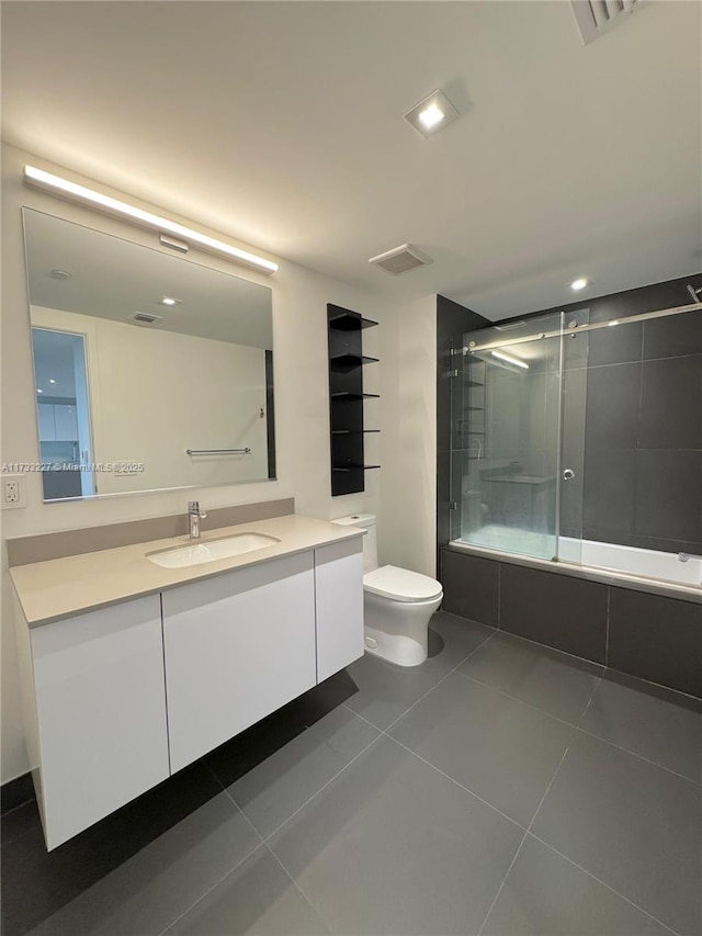 full bathroom featuring toilet, vanity, bath / shower combo with glass door, and tile patterned flooring