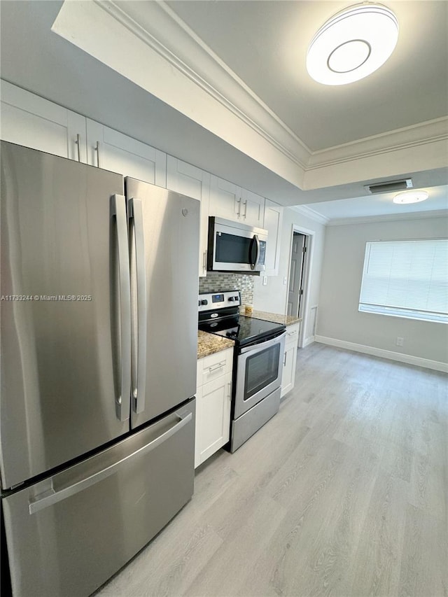 kitchen with light hardwood / wood-style flooring, stainless steel appliances, tasteful backsplash, white cabinets, and a raised ceiling