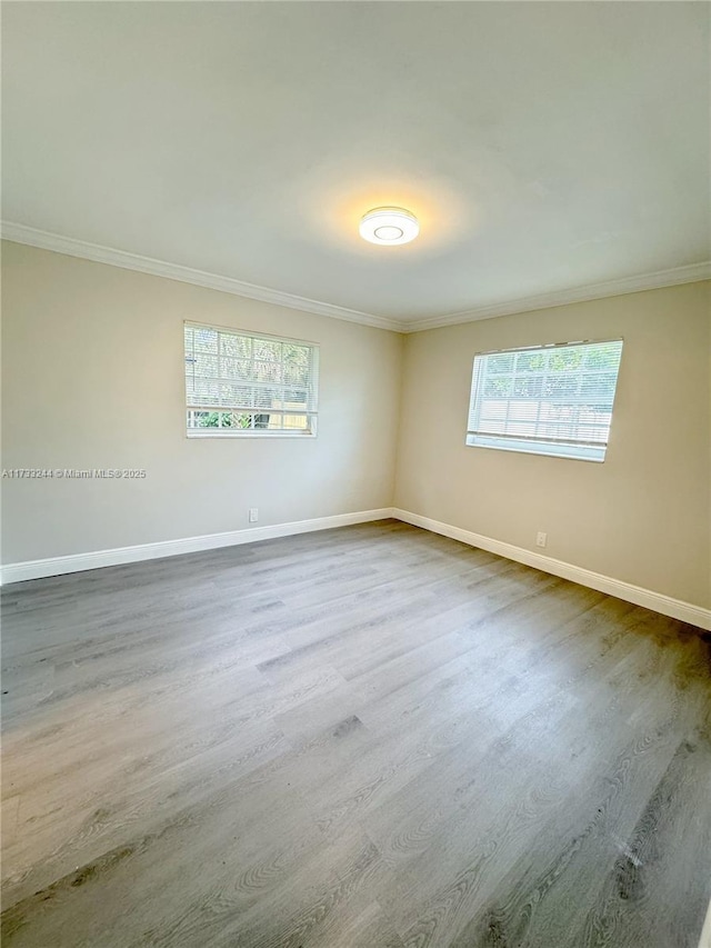 empty room featuring ornamental molding, plenty of natural light, and wood-type flooring