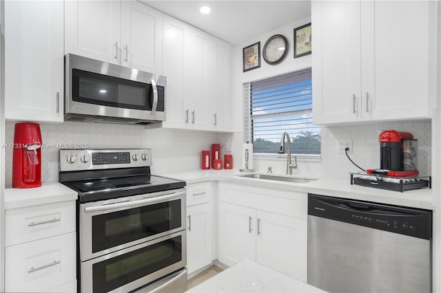 kitchen with sink, backsplash, white cabinets, and appliances with stainless steel finishes