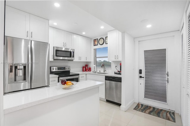 kitchen with white cabinetry, stainless steel appliances, sink, and backsplash