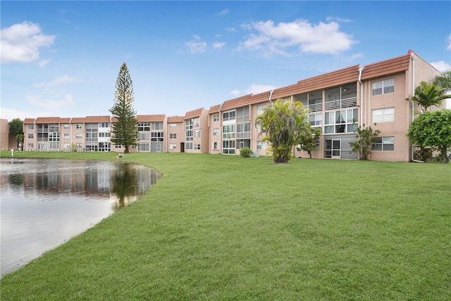 view of property's community with a water view and a lawn