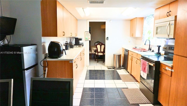 kitchen featuring appliances with stainless steel finishes, sink, and light tile patterned floors