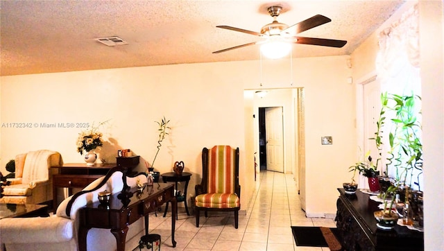 interior space featuring ceiling fan, light tile patterned floors, and a textured ceiling