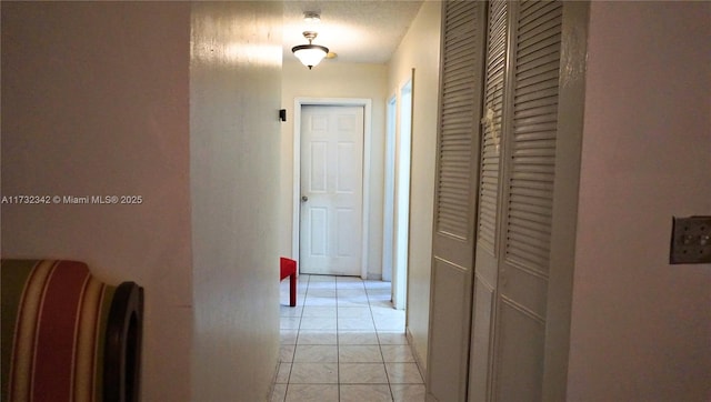 hallway with light tile patterned floors and a textured ceiling