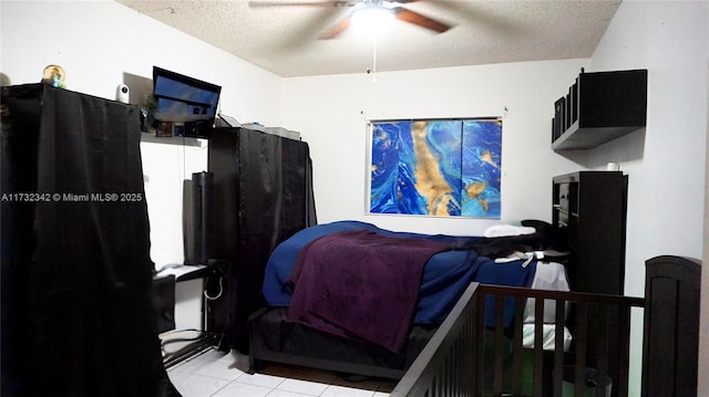 bedroom featuring ceiling fan, light tile patterned floors, and a textured ceiling