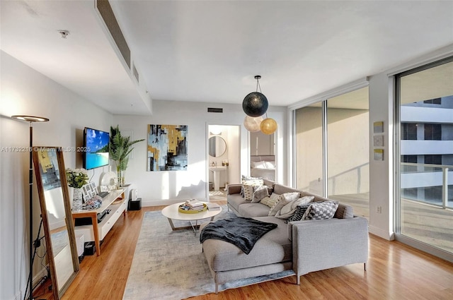 living room featuring floor to ceiling windows, sink, and light hardwood / wood-style flooring