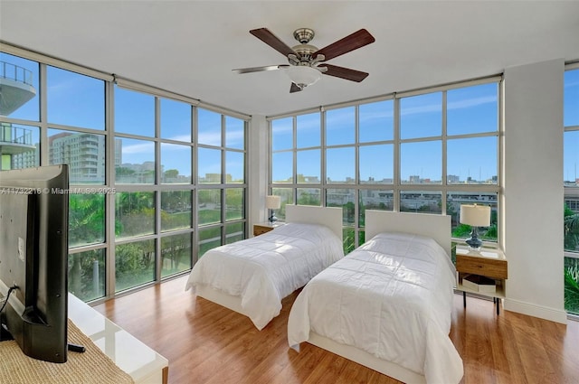 bedroom featuring wood-type flooring, ceiling fan, and a wall of windows