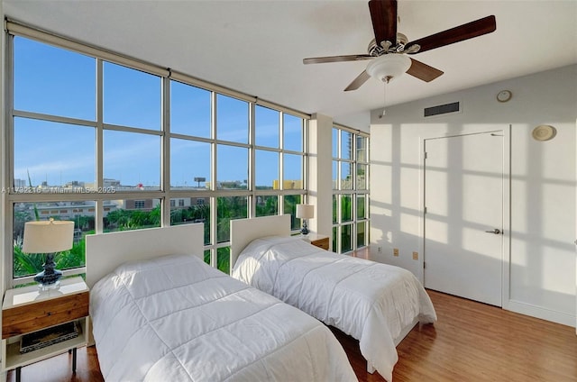 bedroom featuring ceiling fan, floor to ceiling windows, and light hardwood / wood-style floors