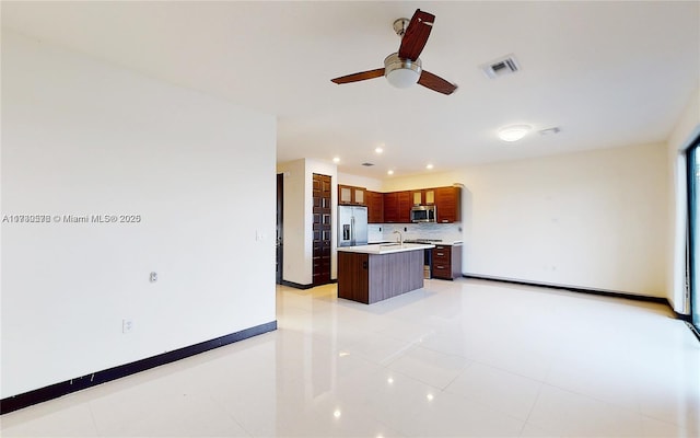 kitchen with light tile patterned flooring, appliances with stainless steel finishes, sink, decorative backsplash, and a kitchen island with sink