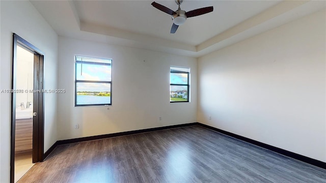 unfurnished room featuring ceiling fan, dark hardwood / wood-style flooring, and a raised ceiling