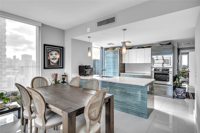 dining room featuring sink, a healthy amount of sunlight, and light tile patterned floors