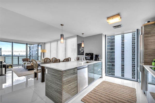 kitchen featuring expansive windows, hanging light fixtures, stainless steel dishwasher, light tile patterned floors, and a water view