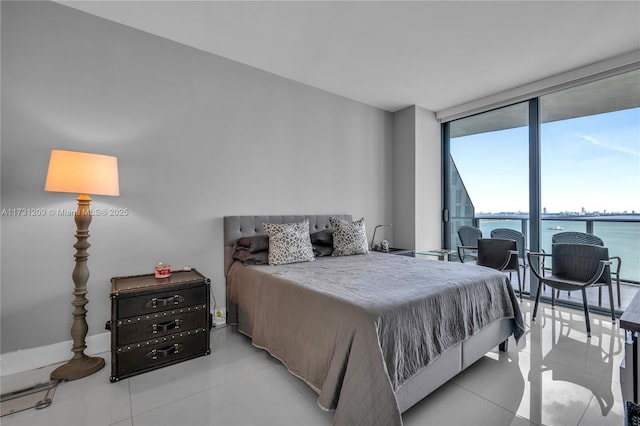 bedroom with light tile patterned floors, floor to ceiling windows, and a water view