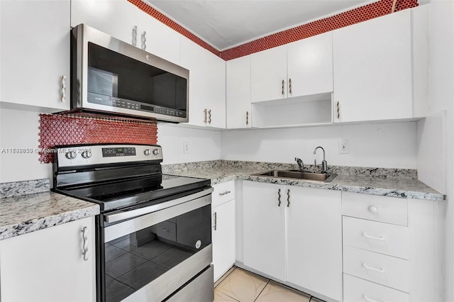 kitchen with light stone counters, stainless steel appliances, sink, and white cabinets