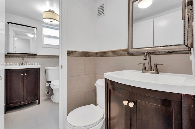 bathroom featuring tile walls, vanity, tile patterned floors, and toilet