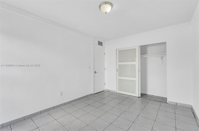 unfurnished bedroom with crown molding and a closet