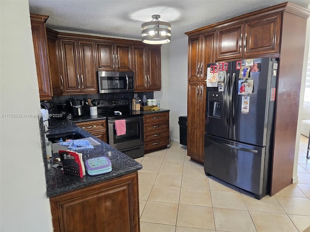 kitchen featuring stainless steel appliances, a textured ceiling, and light tile patterned flooring