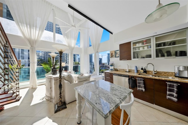 kitchen with dark brown cabinetry, sink, stainless steel dishwasher, and a center island