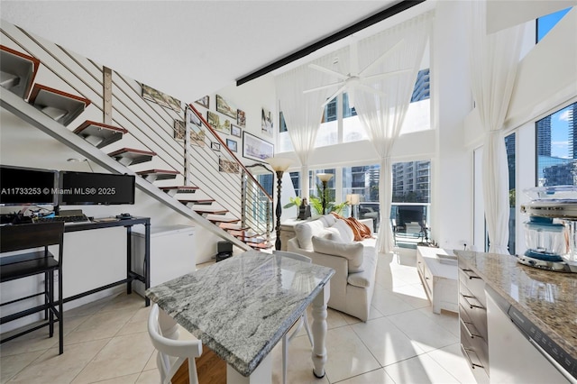 tiled living room featuring beamed ceiling, ceiling fan, and a high ceiling