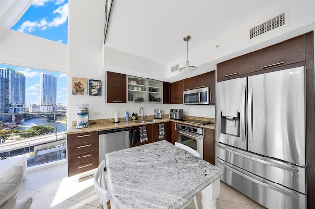 kitchen featuring light tile patterned flooring, sink, a water view, pendant lighting, and stainless steel appliances