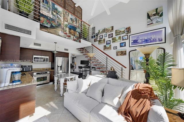 living room with light tile patterned floors, beam ceiling, and a high ceiling