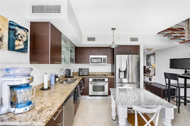 kitchen featuring sink, dark brown cabinets, light tile patterned floors, stainless steel appliances, and light stone countertops