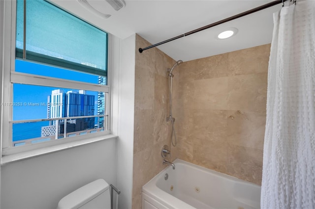 bathroom featuring a wealth of natural light, shower / bathtub combination with curtain, and toilet