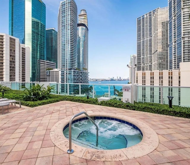 view of swimming pool featuring a water view, a hot tub, and a patio