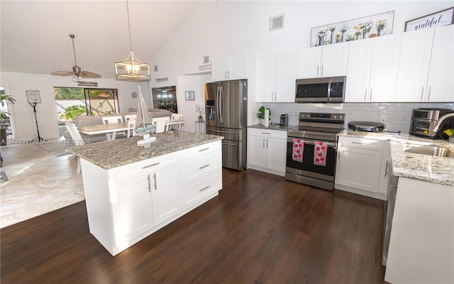 kitchen with white cabinetry, decorative backsplash, stainless steel appliances, and hanging light fixtures