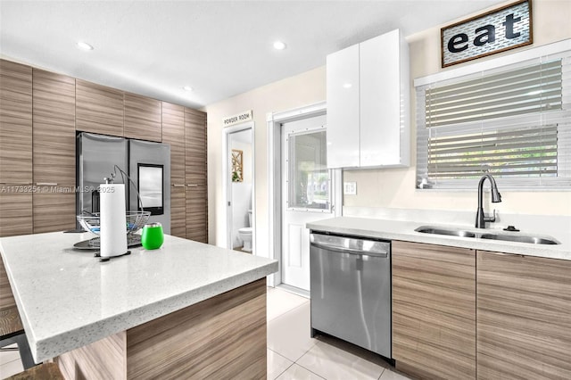 kitchen featuring sink, light tile patterned floors, appliances with stainless steel finishes, white cabinetry, and a kitchen bar