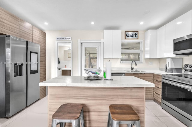 kitchen featuring appliances with stainless steel finishes, a breakfast bar area, and white cabinets