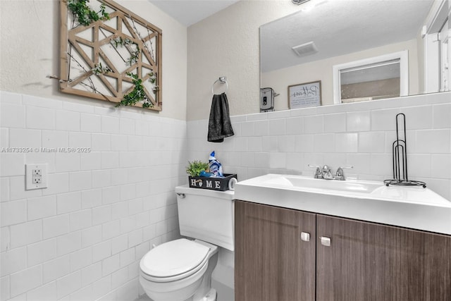 bathroom with tile walls, vanity, and toilet