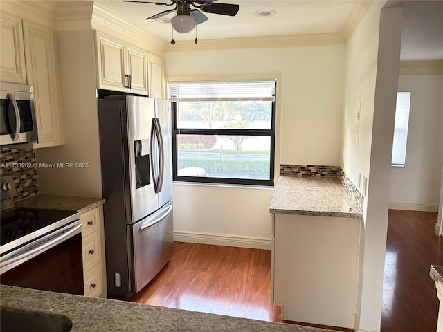 kitchen with light stone counters, ornamental molding, stainless steel appliances, and light hardwood / wood-style floors