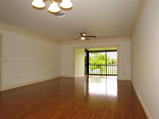 empty room with ceiling fan with notable chandelier, dark wood-type flooring, and ornamental molding