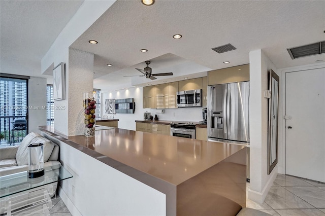 kitchen featuring appliances with stainless steel finishes, kitchen peninsula, a textured ceiling, and light tile patterned floors