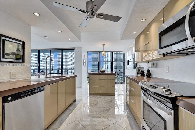 kitchen with sink, ceiling fan, hanging light fixtures, stainless steel appliances, and a textured ceiling