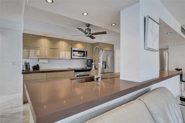 kitchen featuring appliances with stainless steel finishes, light brown cabinetry, sink, ceiling fan, and kitchen peninsula