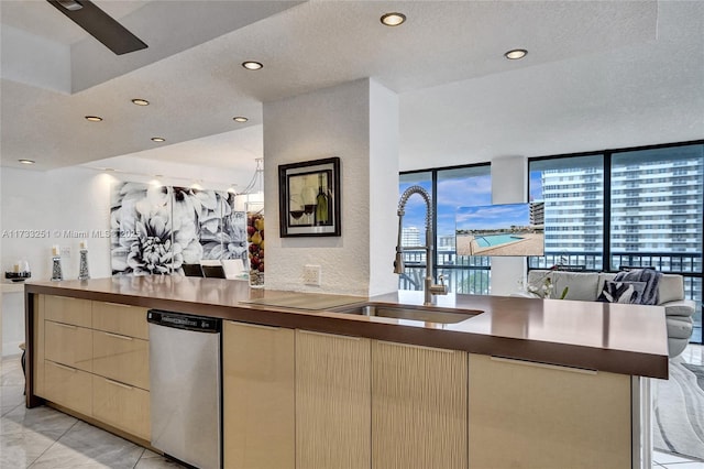 kitchen featuring expansive windows, dishwasher, sink, and light tile patterned floors