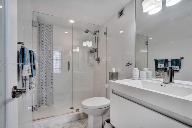 bathroom featuring toilet, vanity, and a shower with shower door