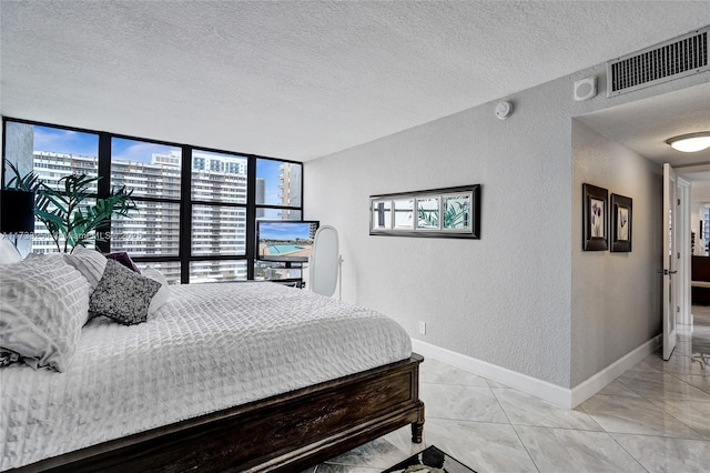 bedroom featuring multiple windows, floor to ceiling windows, and a textured ceiling